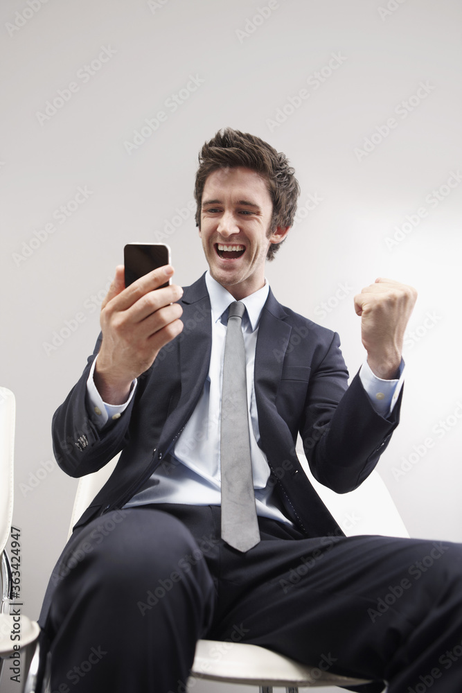 Businessman celebrating after reading the good news on his mobile phone Businessman celebrating after reading the good news on his mobile phone
