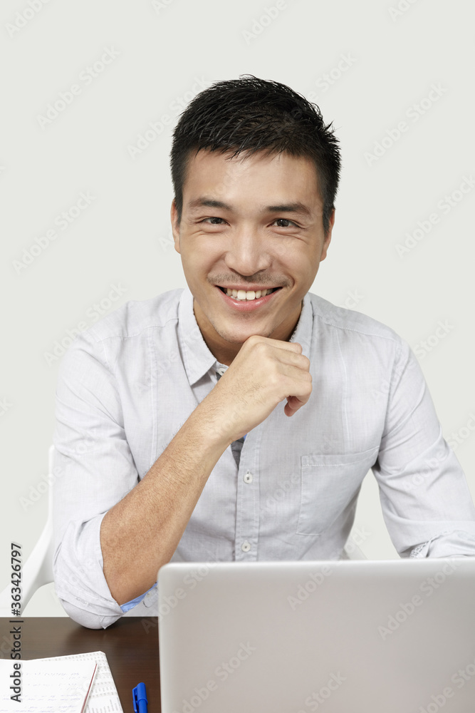 Businessman smiling at the camera while working on his laptop Businessman smiling at the camera while working on his laptop