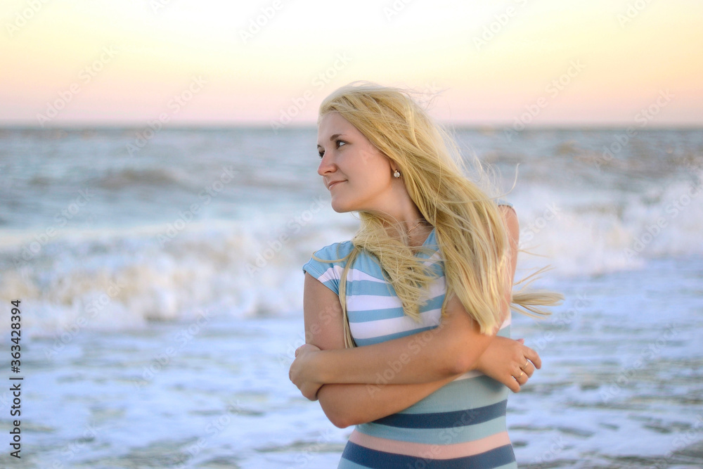 Woman on the beach. Young blonde attractive woman on the background of the sea looks away, half-length portrait.