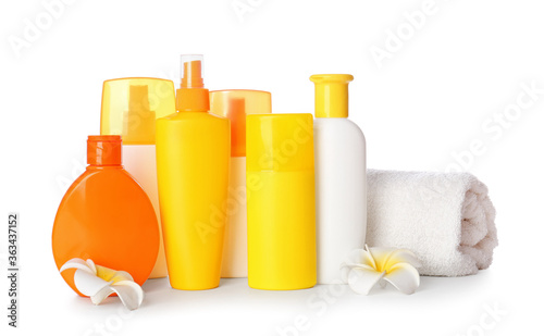 Bottles of sunscreen with towel on white background