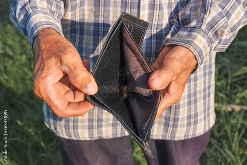 Elderly hands is opening and showing an empty wallet from poverty close-up.