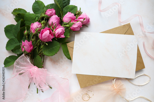 mock wedding card. a bouquet of pink roses, a wedding ring and an envelope with place for text. congratulation. invitation