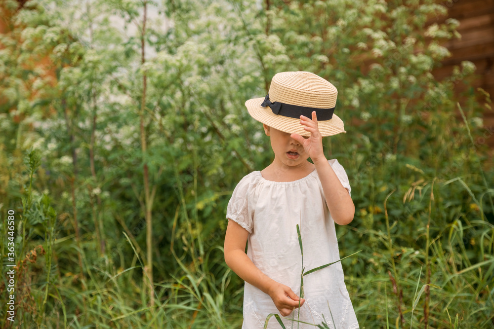 little Girl in a white boho dress with in beautiful green thickets of grass.