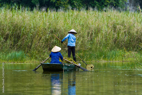 Workers removing algae in the river. Ninh Binh, Vietnam.