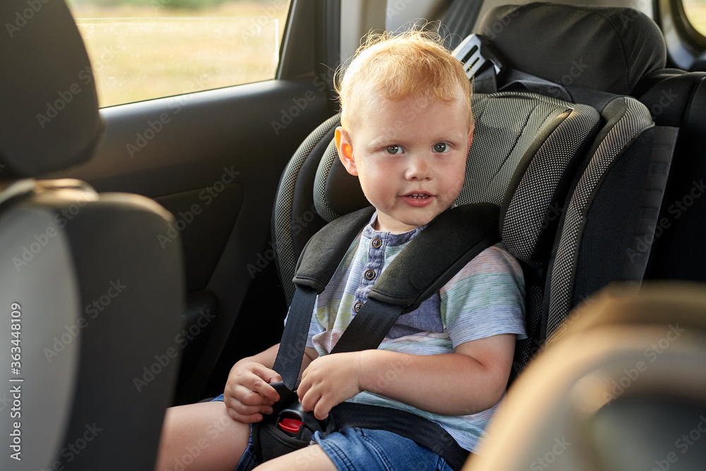 Happy little boy sits in a car seat. Happy little boy sits in a car seat.