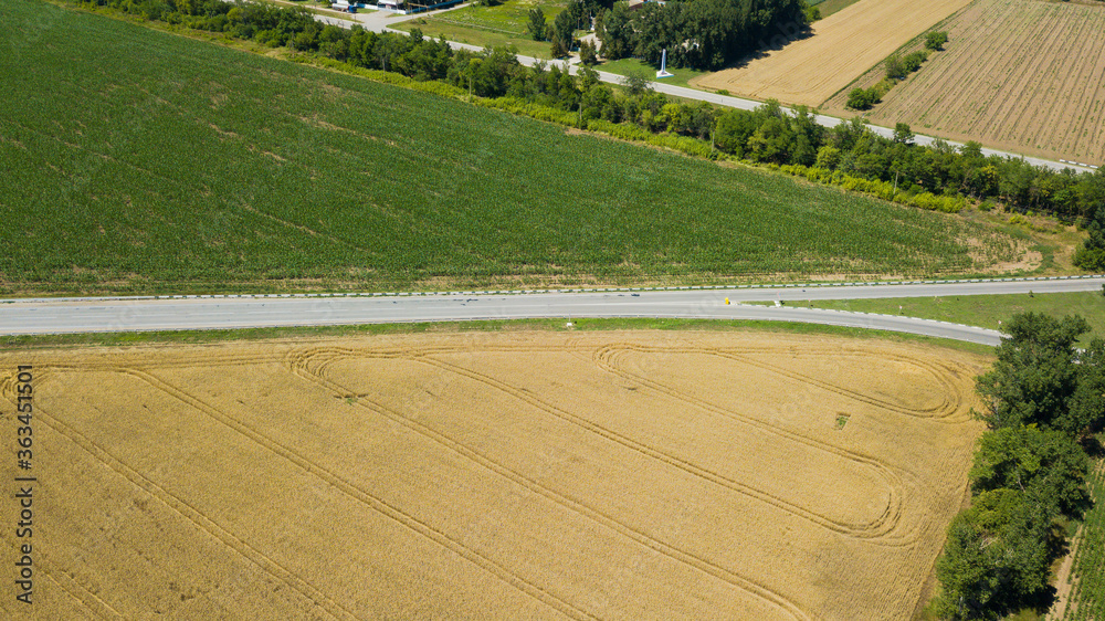 Aerial view of empty highway road between meadow and agricultural field.