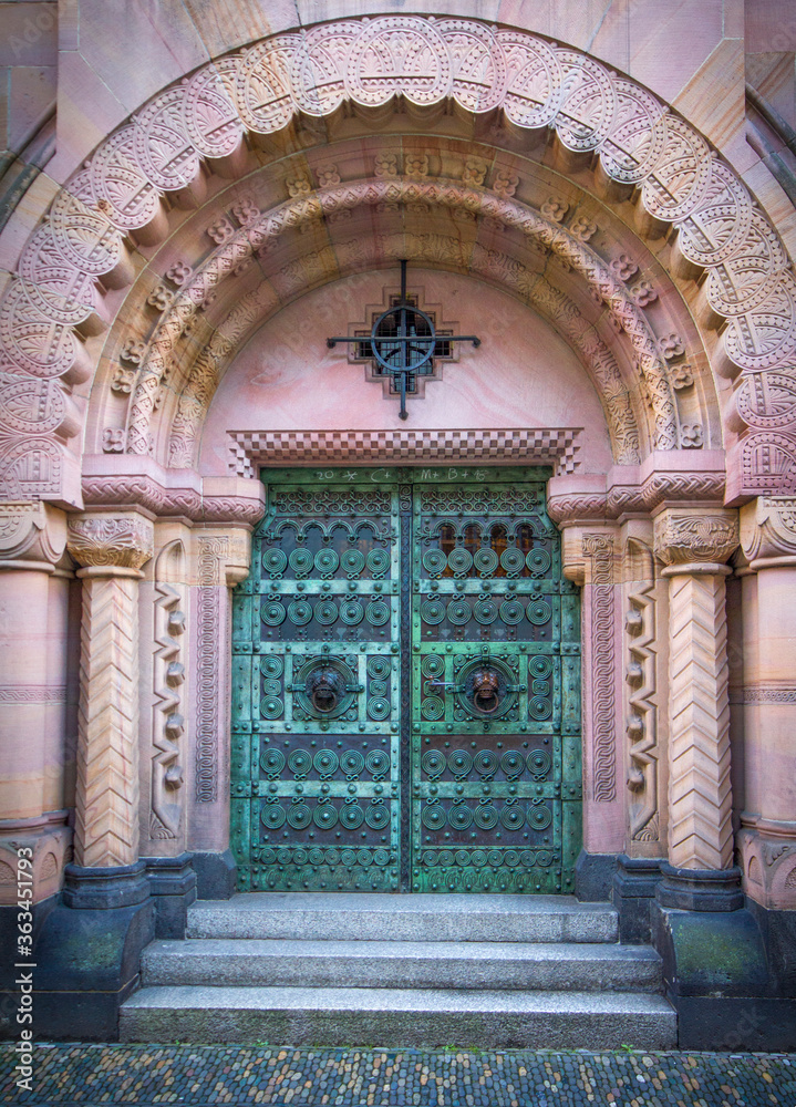 Old, imposing metal gate within a richly ornamented sandstone arch. Freiburg, Germany.