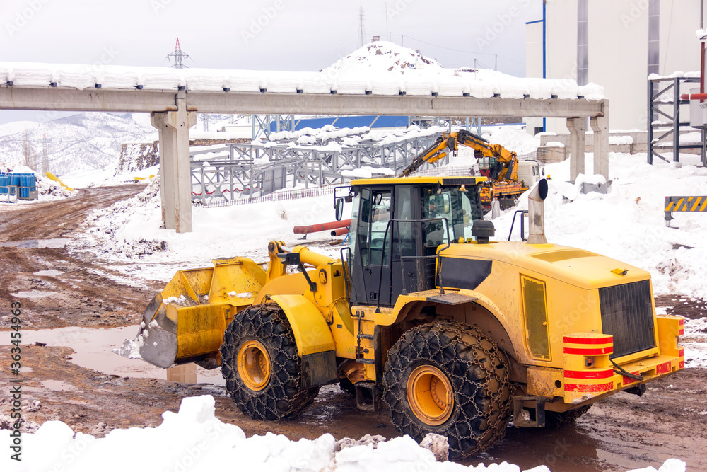 View of the yellow bulldozer in the construction site. A bulldozer or dozer is a crawler equipped with a substantial metal plate used to push large quantities of soil, sand or rubble. View of the yellow bulldozer in the construction site. A bulldozer or dozer is a crawler equipped with a substantial metal plate used to push large quantities of soil, sand or rubble.