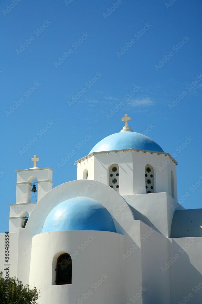 Beautiful white churches of the island of Santorini in Greece with white walls and blue domed roof and bright blue sky behind