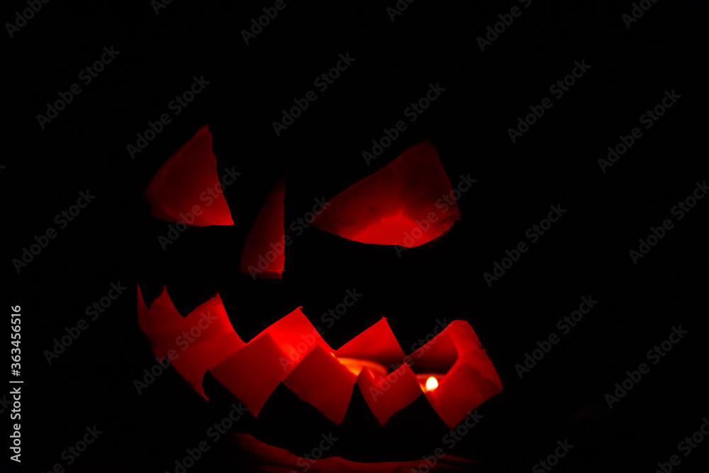 Spooky Halloween pumpkin jack-o-lantern with burning candles on dark background