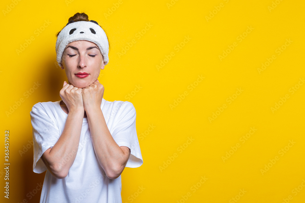 Young woman holds her chin with fists with closed eyes on a yellow background. Young woman holds her chin with fists with closed eyes on a yellow background.
