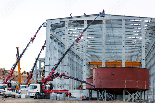 A lot of hiab cranes are working in the construction site. Truck was equipped with a crew compartment behind the driving cab and a HIAB crane for ammunition handling. photo