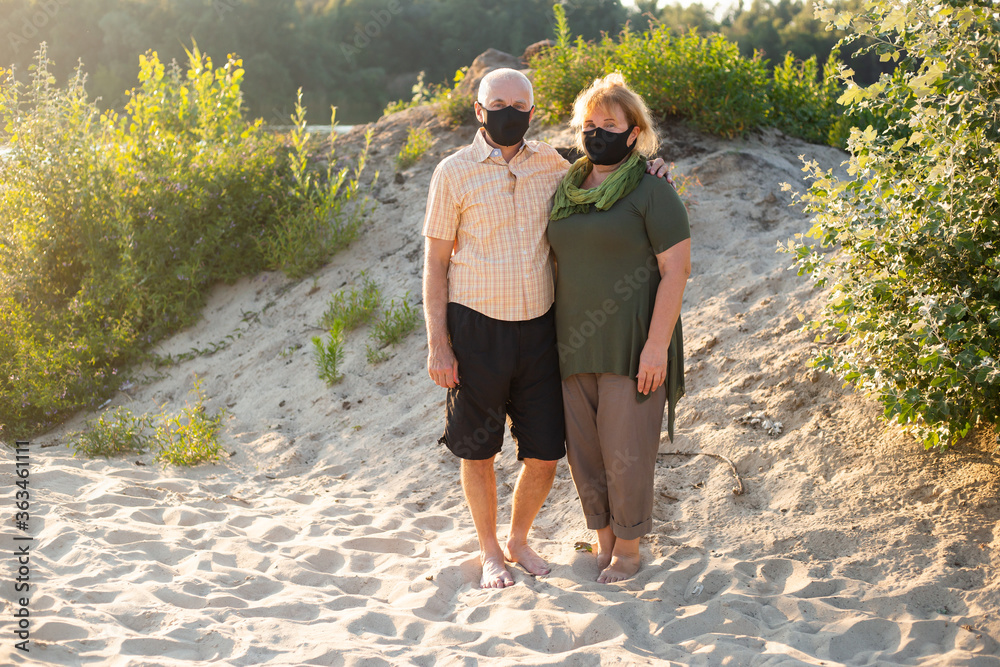 Senior couple wearing medical mask to protect from coronavirus outside in summer nature, coronavirus quarantine