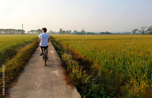 Young man cycling through the chinese countryside at sunset