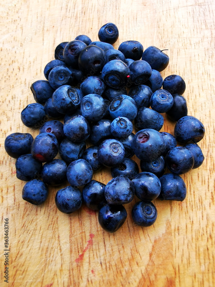 Blueberry (Vaccinium myrtillus) close-up. Berries on a wooden board in the background of green grass. Forest fruits. Blueberry (Vaccinium myrtillus) close-up. Berries on a wooden board in the background of green grass. Forest fruits.