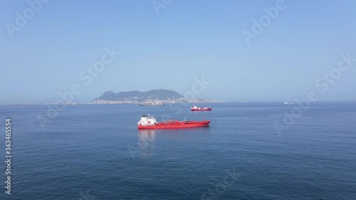 Aerial view with the British Rock of Gibraltar in the background on a cloudless summer day from the air. A few merchant ships are anchored in the foreground.