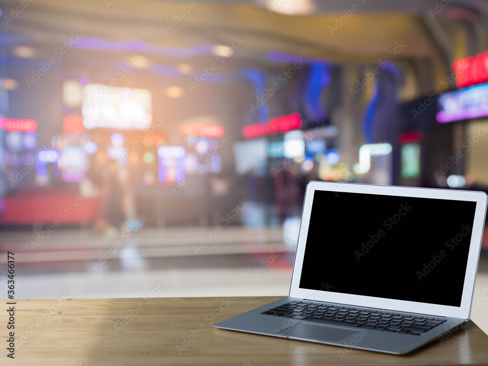 Blank screen laptop computer on wood table top with blur mall with abstract bokeh light defocused background Blank screen laptop computer on wood table top with blur mall with abstract bokeh light defocused background