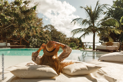 Fotografija Woman in hat taking sunbath near swimming pool