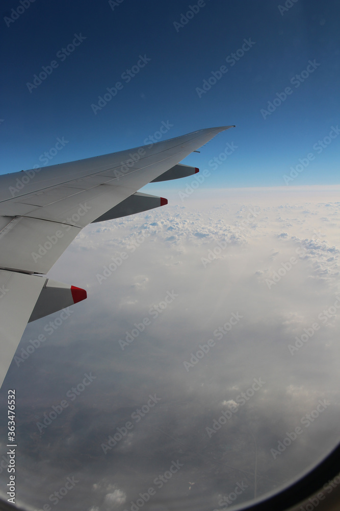 Fototapeta premium Cloud texture and blue sky with wing during sunrise viewed from airplane