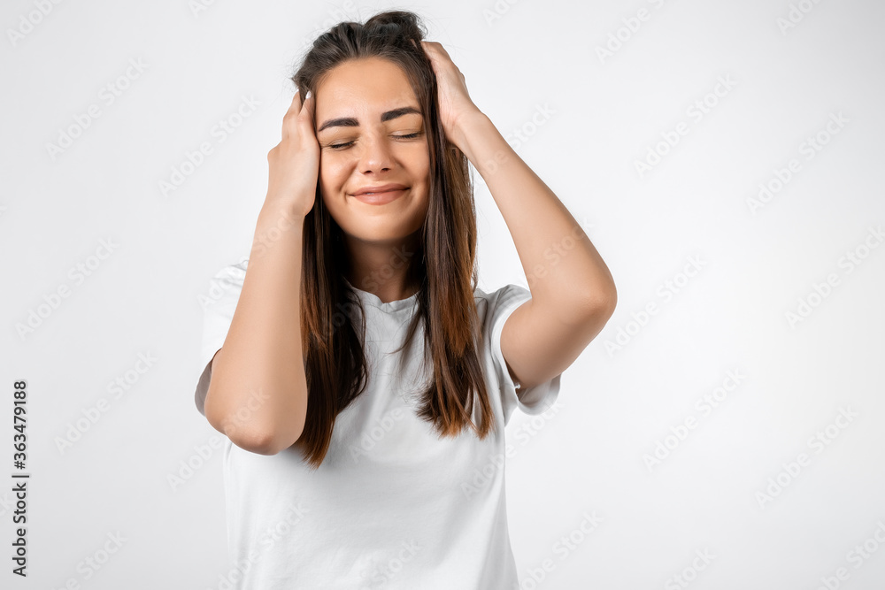 Pretty carefree modern girl with long chestnut hair holding to her head or touching hair. Isolated on white background. Emotions, expressions, hairstyle and people concept. Pretty carefree modern girl with long chestnut hair holding to her head or touching hair. Isolated on white background. Emotions, expressions, hairstyle and people concept.