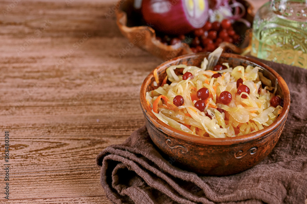 SauPickled cabbage in bowl with wooden spoon and seasoning on dark rustic kitchen table background.Fermented cabbage, german and russian style cuisine. Marinated vegetables. Vegetarian food. SauPickled cabbage in bowl with wooden spoon and seasoning on dark rustic kitchen table background.Fermented cabbage, german and russian style cuisine. Marinated vegetables. Vegetarian food.