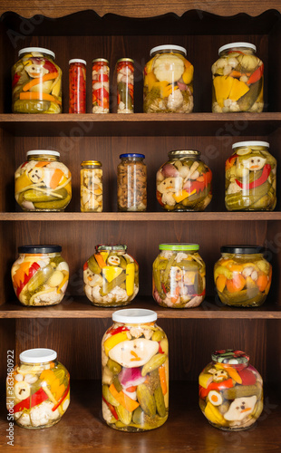 Home Canning of Summer Vegetables Stored on Wooden Shelves. Grandmother's home makings - variety of canned vegetable lined up in rows of glass jars