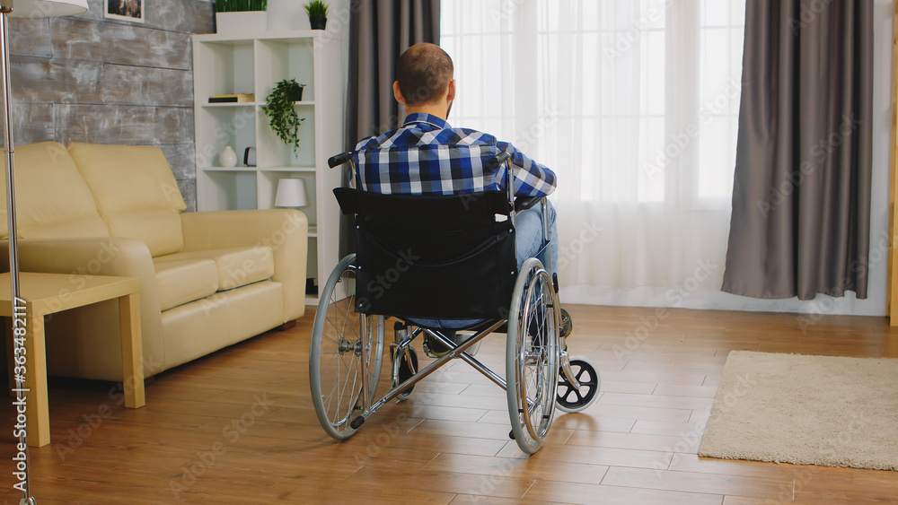 Back view of man with walking disability sitting on wheelchair. Back view of man with walking disability sitting on wheelchair.