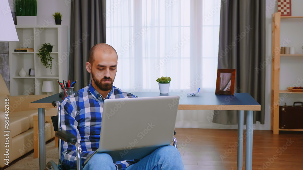 Corporatist in wheelchair working on laptop from home office. Corporatist in wheelchair working on laptop from home office.