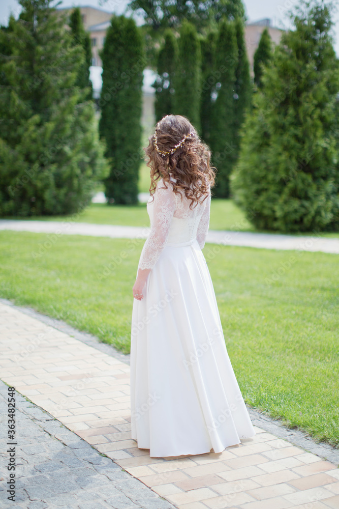 Bride in a white wedding dress stands in the park Bride in a white wedding dress stands in the park
