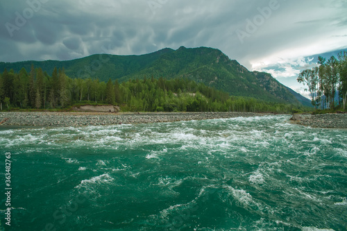 Mountain river with green water. Overcast sky. Thundercloud. © Sergei