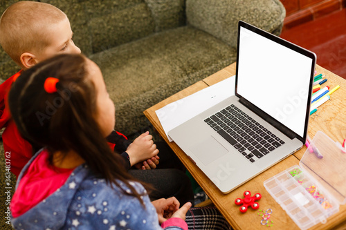 Distance learning online education. school boy and girl studying at home with laptop notebook and doing homework. Sitting at a table photo