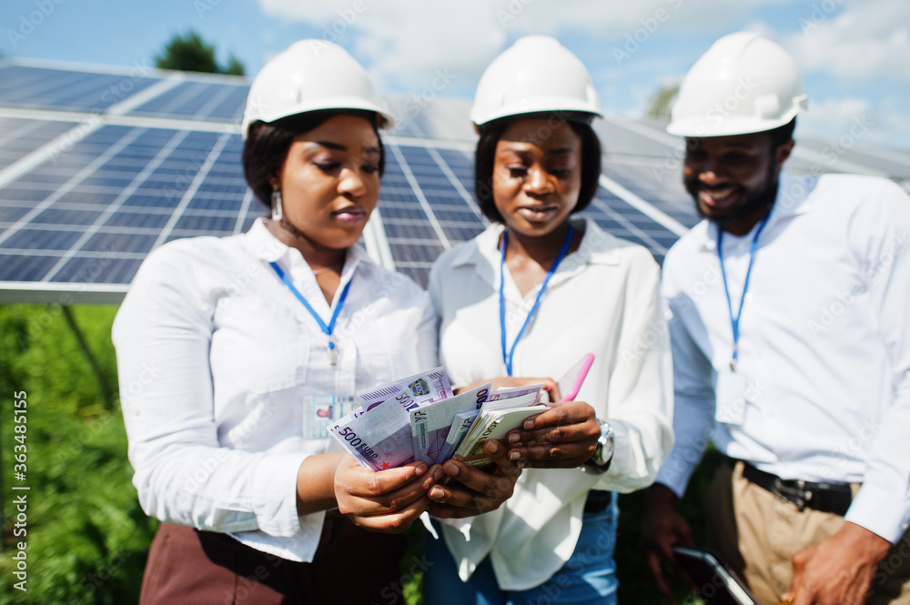 African american technician checks the maintenance of the solar panels. Group of three black engineers meeting at solar station and make a deal with money. African american technician checks the maintenance of the solar panels. Group of three black engineers meeting at solar station and make a deal with money.