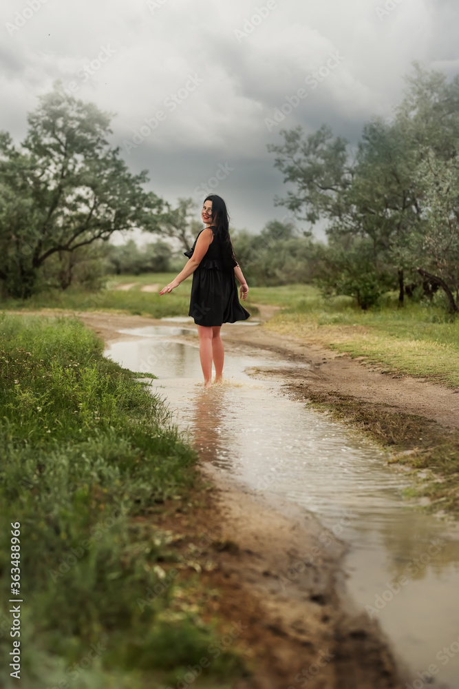 Girl runs on a puddle in nature during the rain.