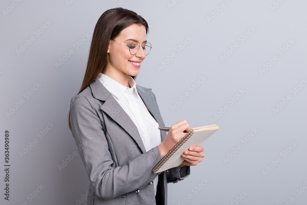 Photo of attractive business lady toothy smile confident manager worker noting writing personal planner interview quotes wear specs shirt checkered blazer isolated grey color background Photo of attractive business lady toothy smile confident manager worker noting writing personal planner interview quotes wear specs shirt checkered blazer isolated grey color background