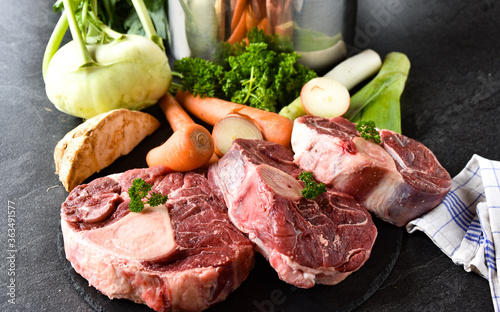 Zutaten für eine Rindfleischsuppe - Rinderbeinscheibe und Gemüse roh und ungekocht photo