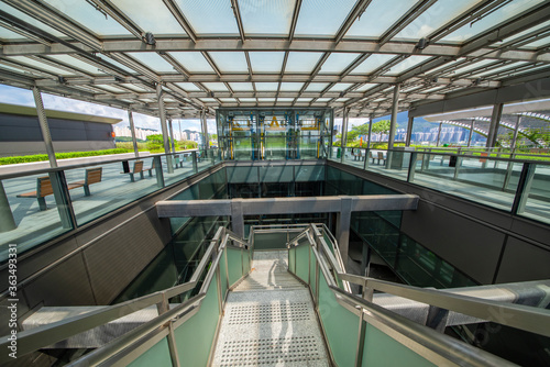 Modern glass elevator and pedestrian stairway entrances.