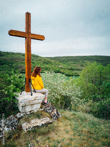 femme assis devant une croix dans la montagne photo