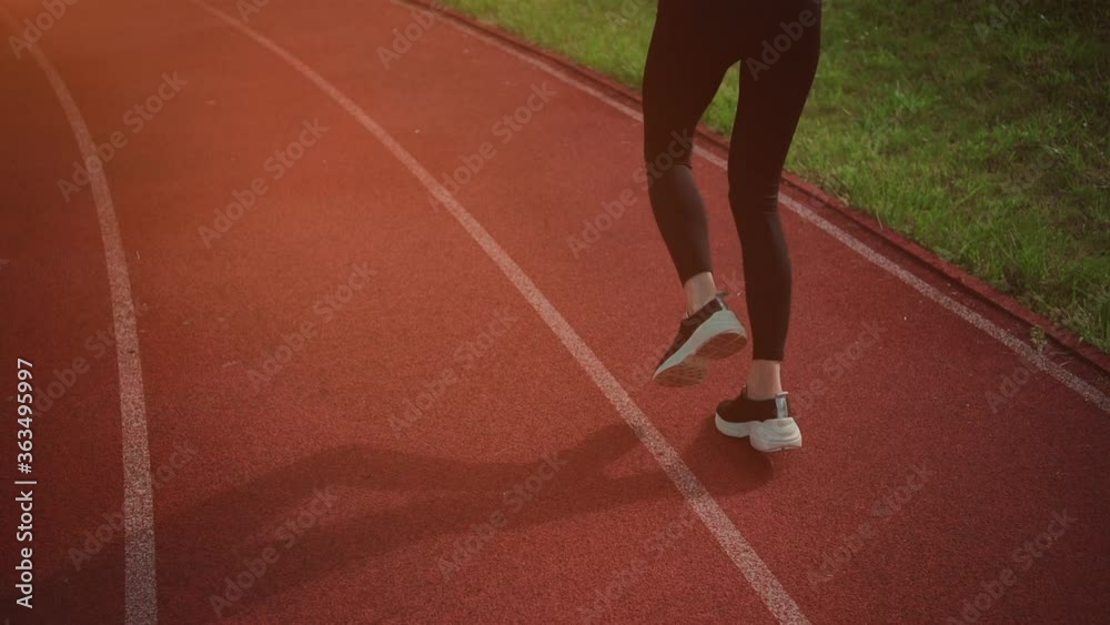 rear view of athletic woman running on track stadium at summer rear view of athletic woman running on track stadium at summer
