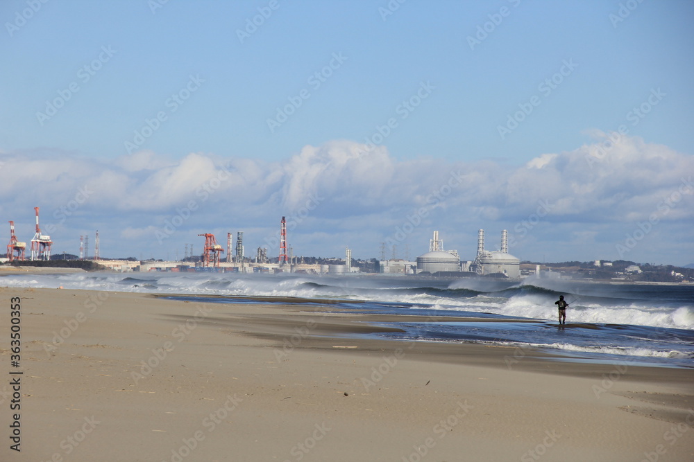 遠くに発電所などが見える海岸の風景