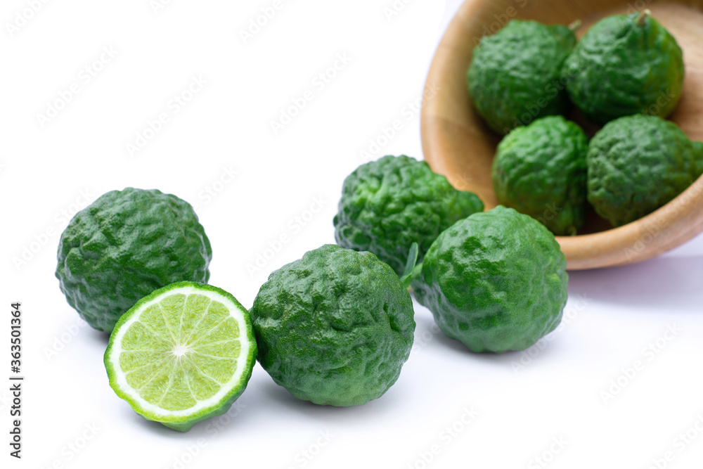 Obraz premium Bergamot or kaffir lime fruits with green leaf in wooden bowl isolated on white background. 