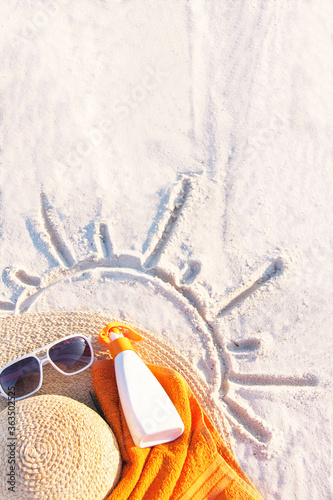 Sand texture with hat, towel, sunscreen and sunglasses on the a beach.