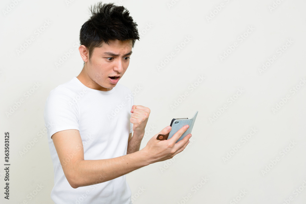 Portrait of young handsome Asian man using phone Portrait of young handsome Asian man using phone