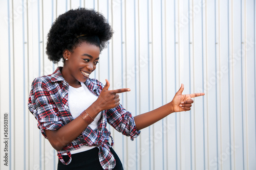Promotion concept. Cheerful african american woman pointing aside on free space, recommending something. Grey background.