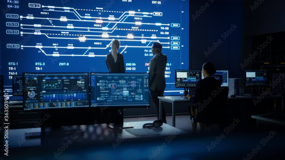 Project Manager and Computer Science Engineer Talking while Using Big Screen Display Showing Infrastructure Infographics and Data.Telecommunications Company System Control and Monitoring Room