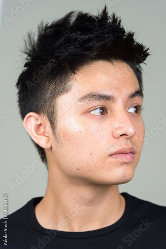 Face of young handsome Asian man thinking