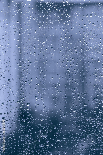 rainy droplets on a blue window glass transparent surface. drops on window shield in a rainy days in night city. stormy weather. isolation sad depression concept. rainy season.