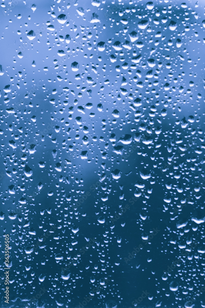 rain drops on a blue window glass transparent surface. water droplets on dripped window shield in a rainy days in autumn spring summer winter in night. stormy weather. depression concept.