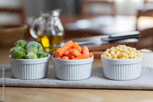 Frozen vegetables such as baby carrot and and Brussels sprouts in the bowls on the kitchen table  horizontal