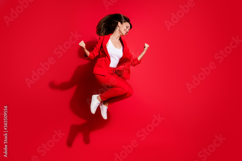Full body photo of attractive lady successful worker having fun jumping high up good mood celebrating startup success wear blazer suit pants footwear isolated bright red color background