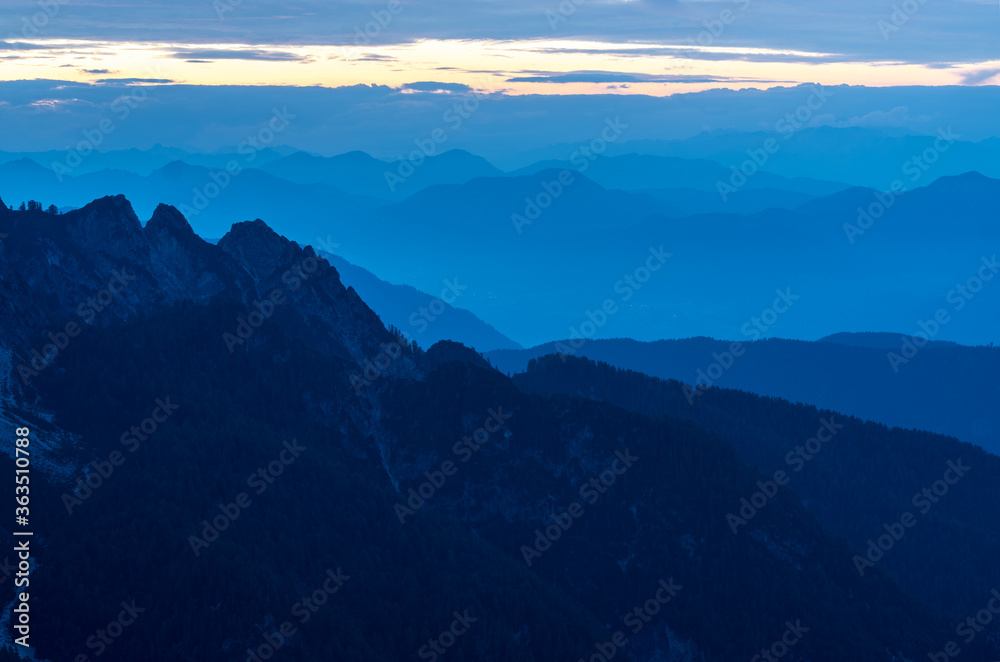 Spectacular view of blue mountain ranges silhouettes and fog in valleys. Julian Alps, Triglav National Park, Slovenia. View from Mountain Slemenova, Sleme.